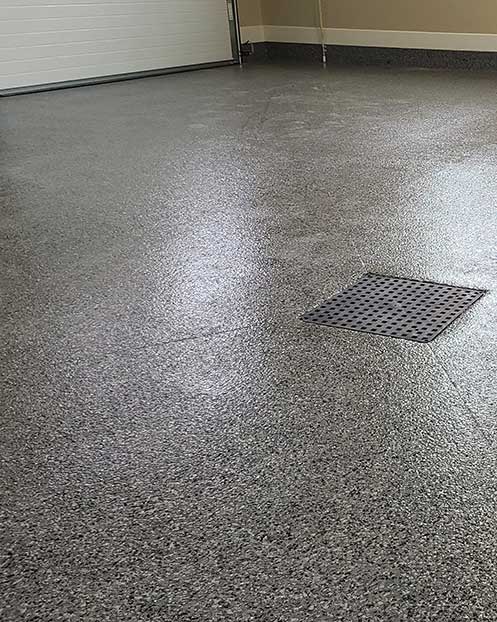 Polyaspartic coating on garage floor with square drain in center of floor