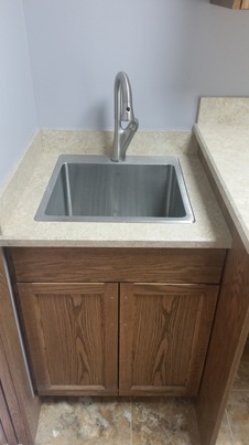 small laundry sink with high tap and lower storage cabinet