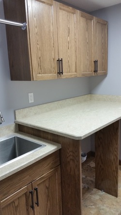 Countertop over space for washer and dryer, cabinets, sink and clothes hanging bar