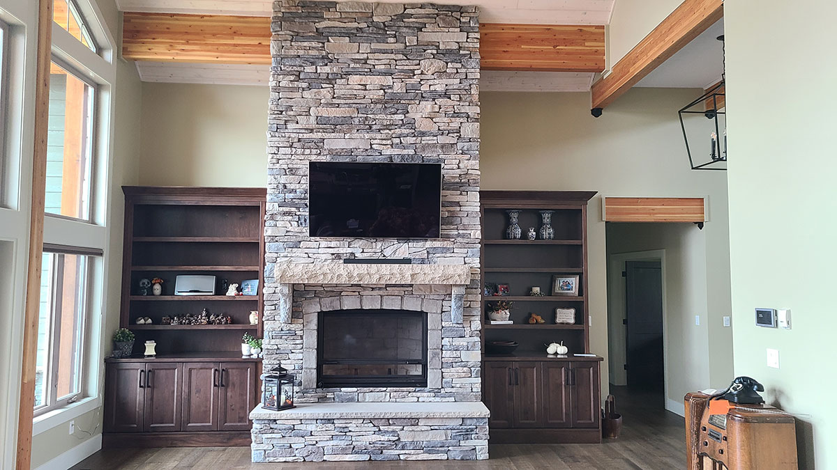 Stone fireplace with TV above mantel and cutom maple hutches on either side