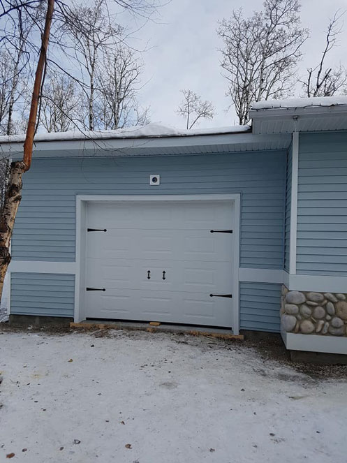 Attached garage in light blue with white overhead door