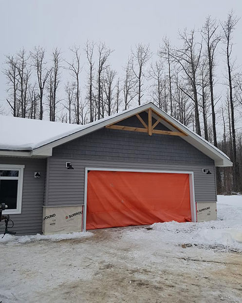 Double car garage being built with tarp for protection from weather
