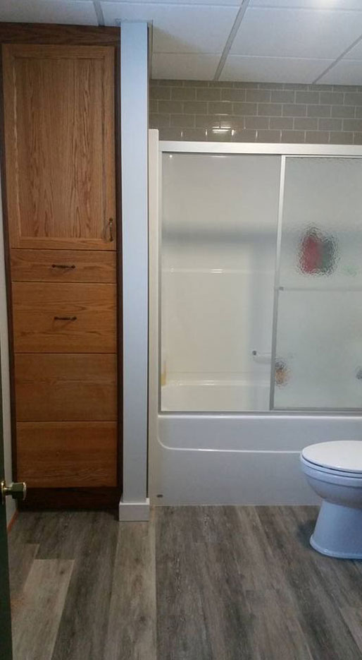 Basement bathroom addition with custom cabinet and glass shower doors