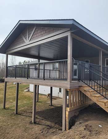 Covered deck with gated stairs and metal railings over a walk-out basement