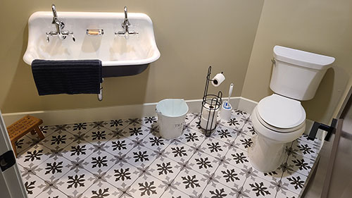 bathroom with large wallmount sink and toilet and black, grey and white tile floor