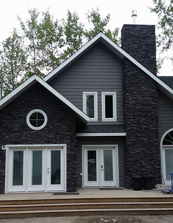 Sharp contrast of slate rock siding on dark gray house