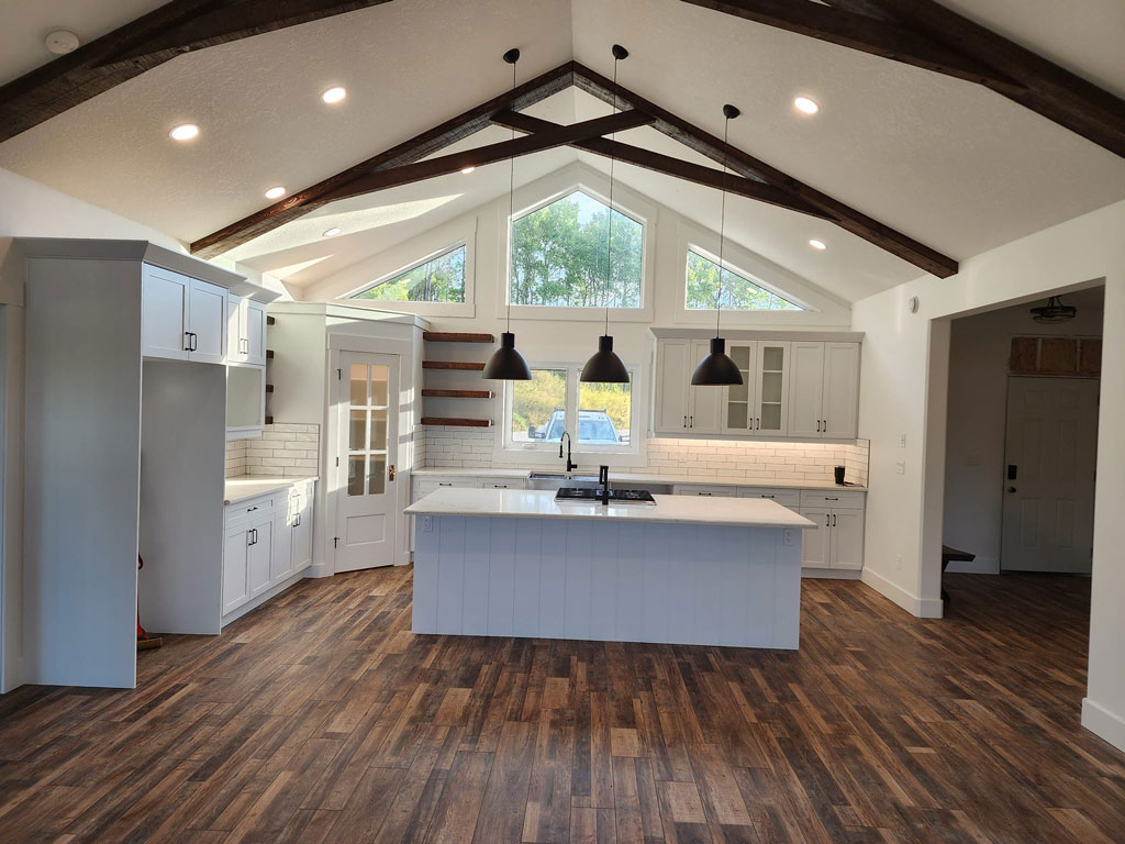 White kitchen with dark wood exposed beams on a vaulted ceiling