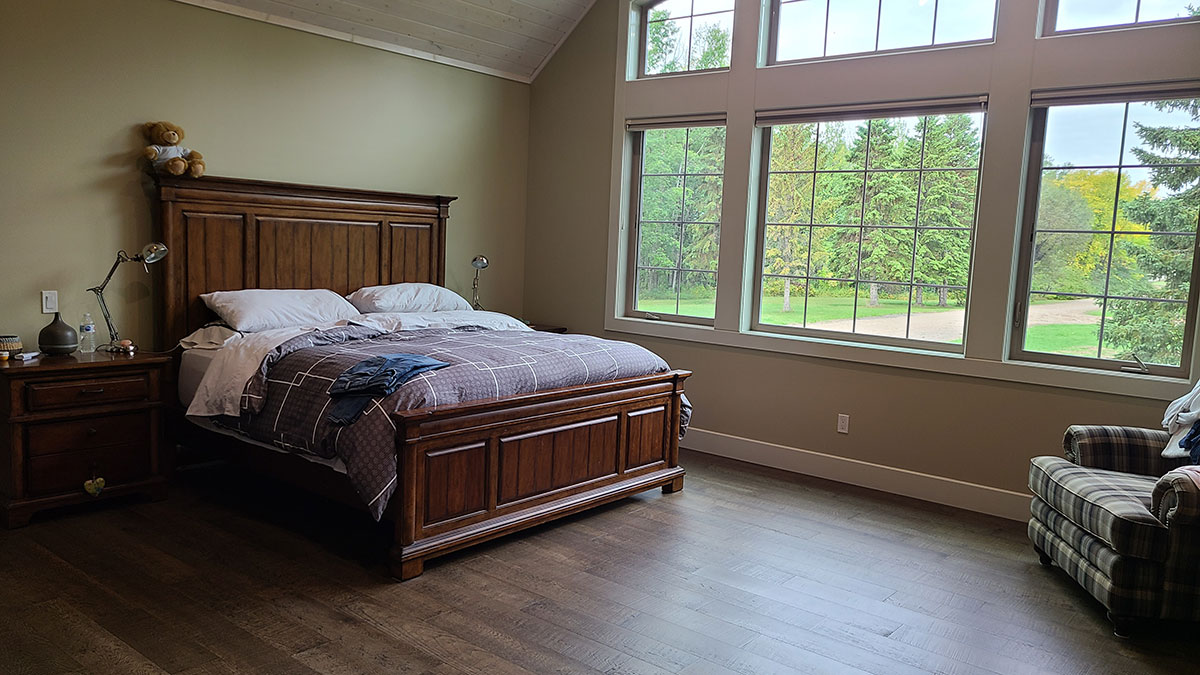 master bedroom with large vaulted windows and hardwood flooring