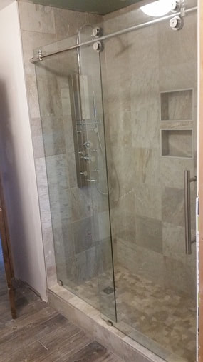 Shower stall with custom pebble mosaic floor, tiled walls and shampoo niche and double glass doors