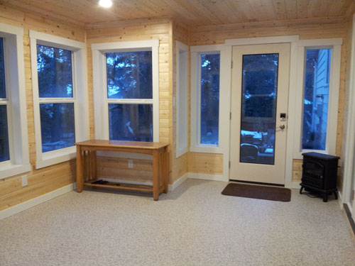 Sunroom with pine walls and white framed windows and door