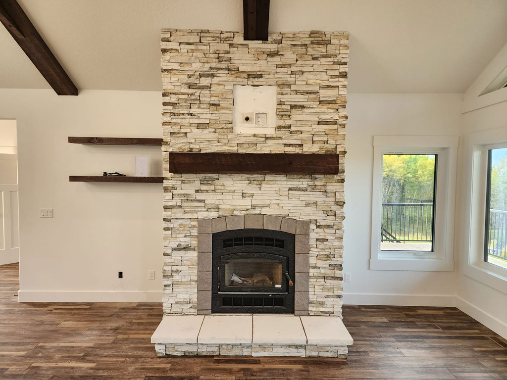 Warm stacked stone fireplace with dark wood mantel