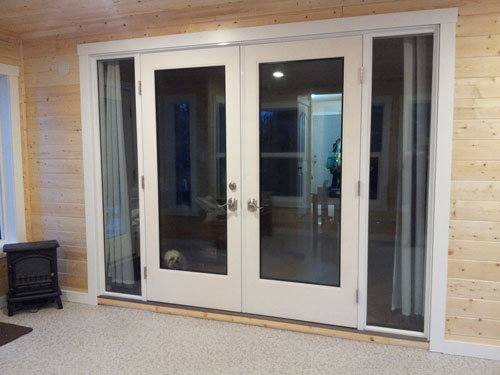 Double french doors with side panels in a pine wood sunroom