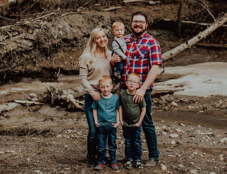 ​Tanner and Jenna Merriam with their 3 boys beside a creek