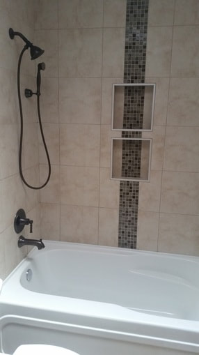 white bathtub with beige tile surround and mosiac tile accent niche