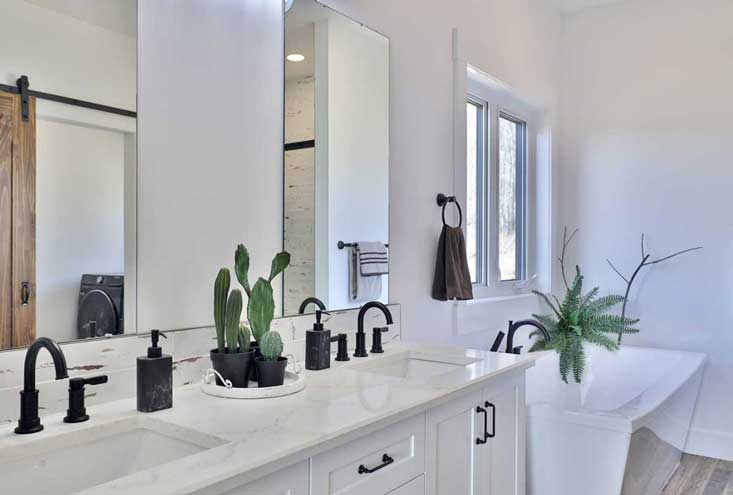 Bathroom with white cabinets and counter-tops is next to free-standing white rectangular bath tub
